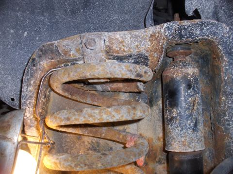 1994 Ford F-150 - The front suspension coil spring and shock absorber show significant rust and wear.
