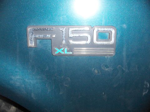 1994 Ford F-150 - Close-up of the F-150 XL badge on a teal Ford truck, confirming the model and trim.