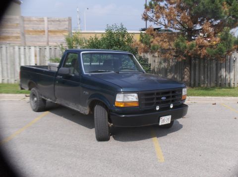 1994 Ford F-150 - A dark green 1994 Ford F-150 pickup truck is parked in an outdoor lot.