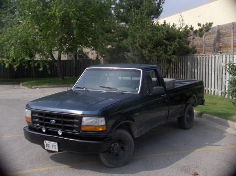 1994 Ford F-150 - A dark blue Ford F-150 pickup truck is parked in an outdoor lot, viewed from the front three-quarter angle.