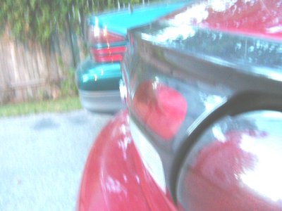 1997 Ford Taurus - Rear view of a red car, with a teal car visible behind it. The image contains a watermark.