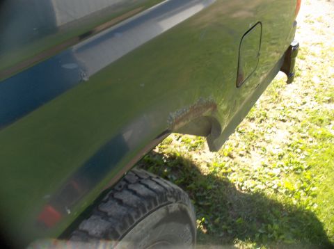 1994 Ford F-150 - Close-up view of the rear fender and tire of a green truck, showing signs of rust.