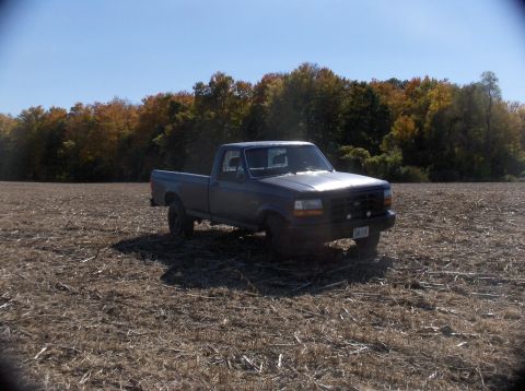 1994 Ford F-150 - A 1994 Ford F-150 pickup truck sits in a harvested field under a clear blue sky.