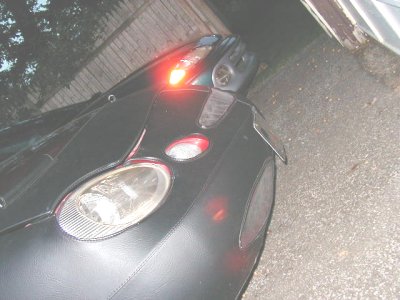 1997 Ford Taurus - The front of a car is covered in black material, with a red brake light illuminated.