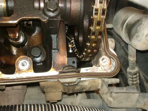 1998 Ford Crown Victoria - Engine timing chain and valve cover gasket detail. Oil is present on various engine parts.
