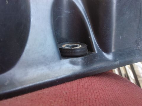 1998 Ford Crown Victoria - A rubber grommet is visible on a black plastic component, with a red fabric surface below.