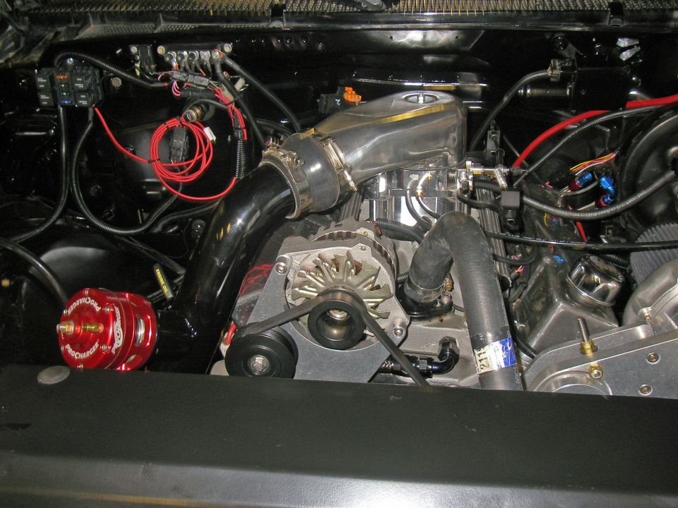 Supercharged V8 engine bay with red ProCharger bypass valve, black charge pipe and polished intake