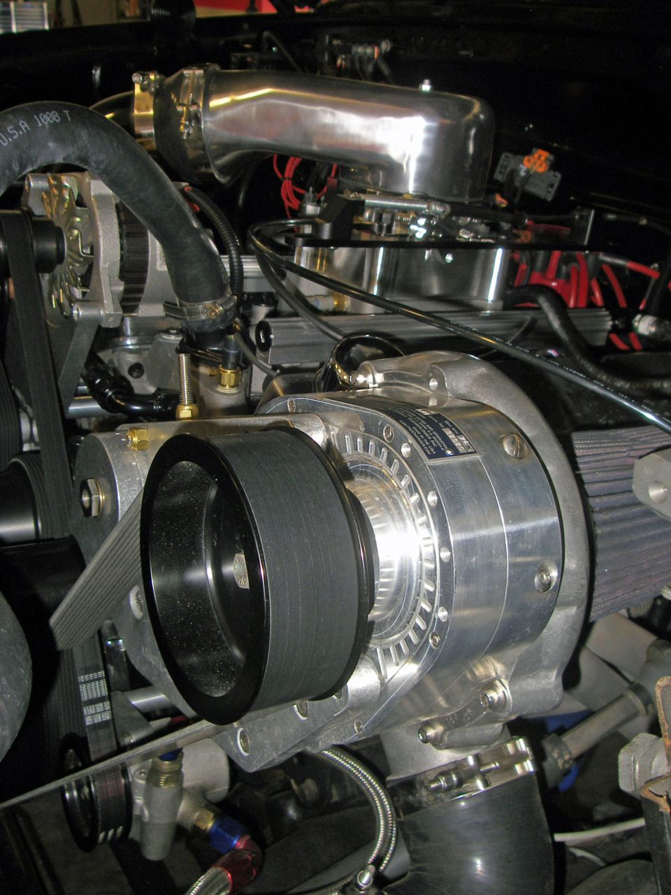 Close-up of a supercharger, alternator, and intake manifold on an engine