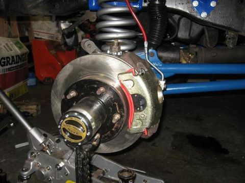 1993 Ford Bronco - A close-up view of a vehicle's front brake assembly, a WARN locking hub and suspension components.