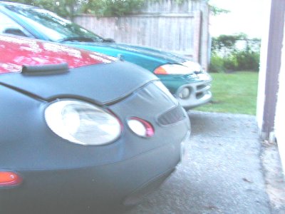 1997 Ford Taurus - Front view of a 1997 Ford Taurus with a car cover, parked next to another vehicle.