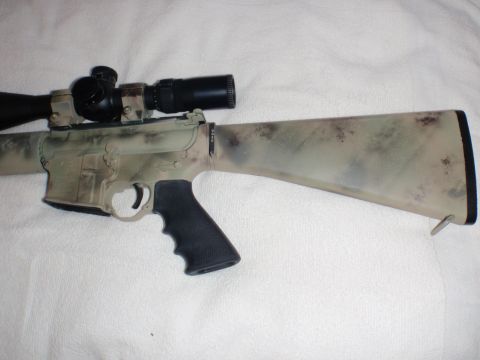 1991 Ford Bronco - A rifle with a camouflage pattern and a mounted scope is shown against a white background.