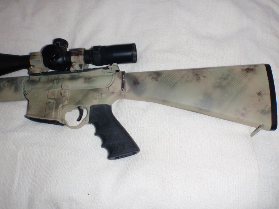 Camouflaged rifle with scope and black grip