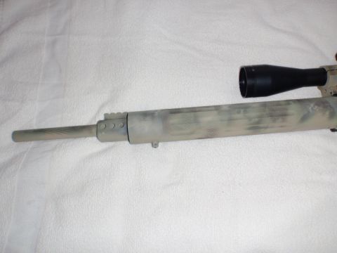 1991 Ford Bronco - Close-up of a rifle barrel with a camouflage paint job and a black scope.