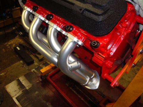 1989 Ford Bronco - Close-up view of a red engine block with newly installed silver exhaust headers.