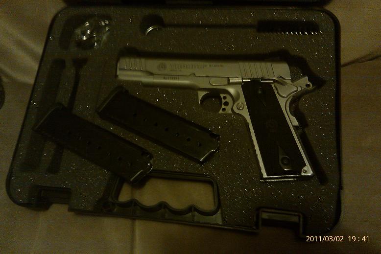 Pistol with two magazines and cleaning brush in a fitted case