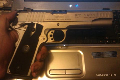 2000 Mercury Grand Marquis - A hand holds a Taurus PT 1911 pistol over a laptop keyboard.