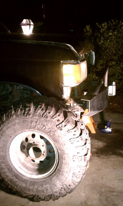 1990 Ford Bronco - Front end of a 1990 Ford Bronco undergoing work, showing large tires and custom bumper.