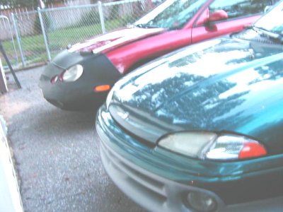1997 Ford Taurus - Two cars parked in a driveway, one is a 1997 Ford Taurus.