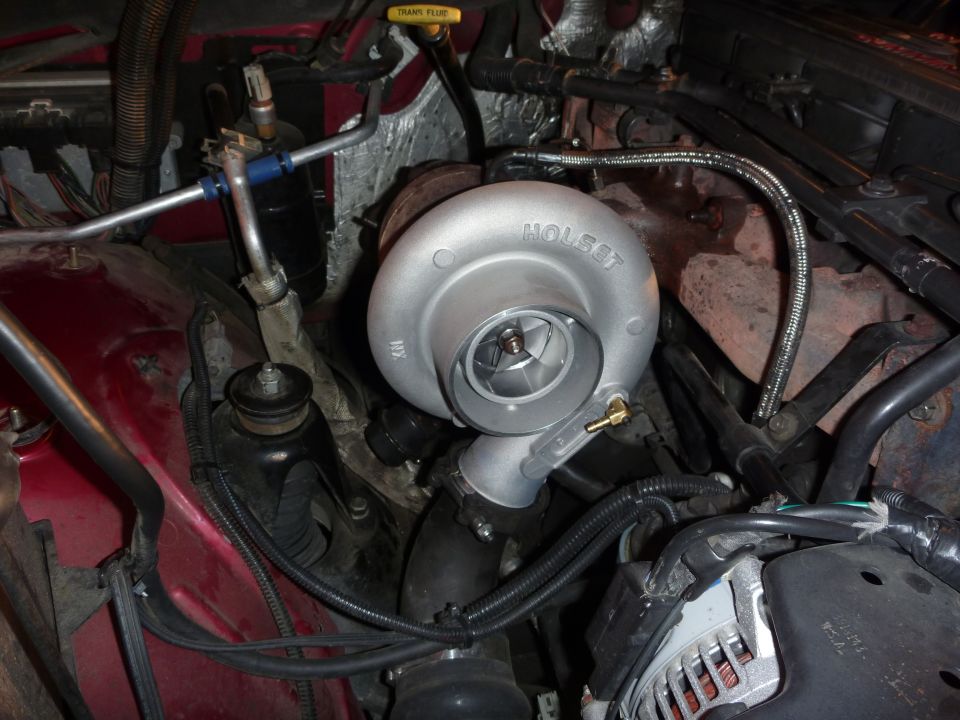 Engine bay with a silver Holset turbocharger, red fender, and black hoses