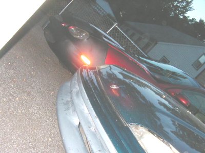 1997 Ford Taurus - Two cars are parked closely together in a driveway, with one's turn signal illuminated.