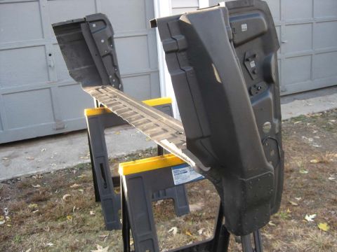 1983 Ford Bronco - Two black-painted rear inner wheel-house and quarter panel structures and a bare tread-patterned rail set up on yellow-and-black plastic sa…