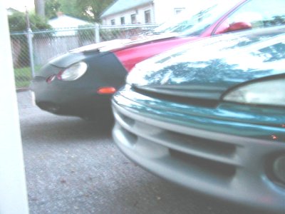 1997 Ford Taurus - Two cars are parked in a driveway, one teal and one red and black.