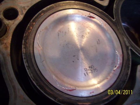 1995 Ford Probe - Close-up of a piston showing wear marks and stamped numbers '0.50 11-775'.