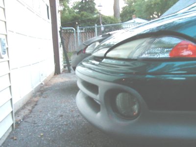 1997 Ford Taurus - A green car's front end is parked next to a building, with another vehicle visible behind it.