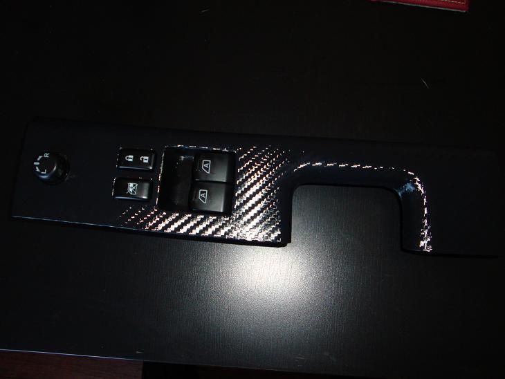 Door window switch panel with carbon-fiber DI-NOC wrapped bezel and mirror selector knob