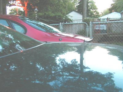 1997 Ford Taurus - Two cars are parked in a residential area with a fence and houses in the background.