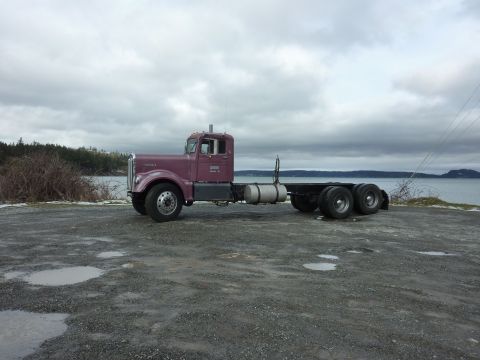 1959 Kenworth W900A - A 1959 Kenworth W900A semi-truck cab and chassis is seen parked outdoors with a body of water in the background.