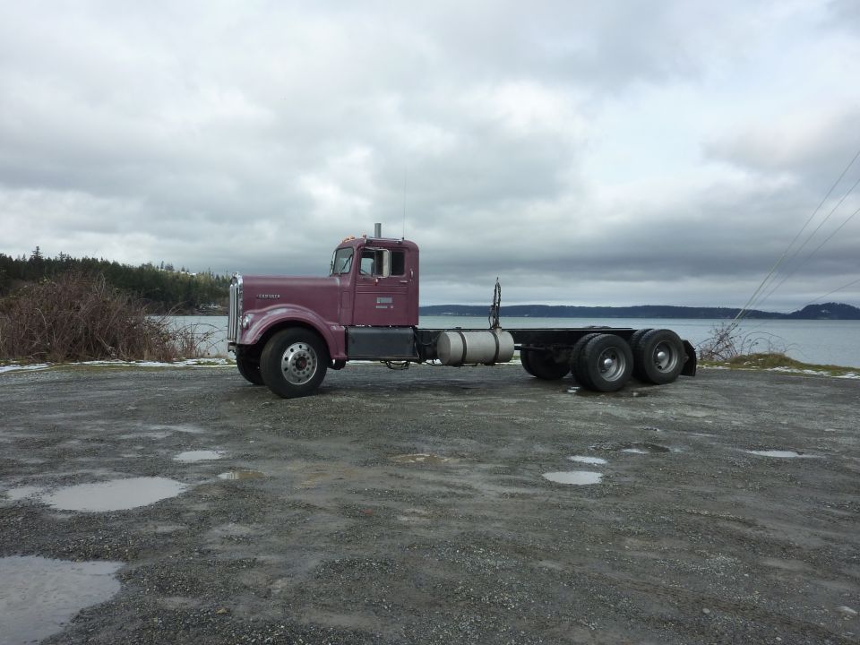 Purple 1959 Kenworth W900A semi-truck cab and chassis parked by the water