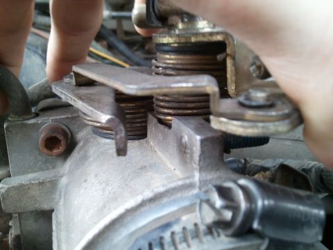 1989 Ford Bronco - Throttle body linkage mechanism with springs and a lever being adjusted.