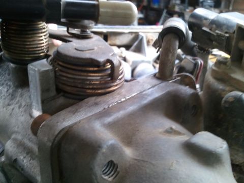 1989 Ford Bronco - This is a close-up view of a vehicle's throttle body assembly, showing mechanical parts and springs.
