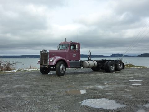 1959 Kenworth W900A - A 1959 Kenworth W900A semi-truck chassis is parked outdoors with a cloudy sky and water in the background.