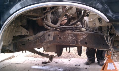 1990 Ford Bronco - Close-up view of a vehicle's undercarriage, showing rusted frame and engine components.