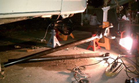 1990 Ford Bronco - The underside of a vehicle is shown supported by jack stands as it undergoes repairs.