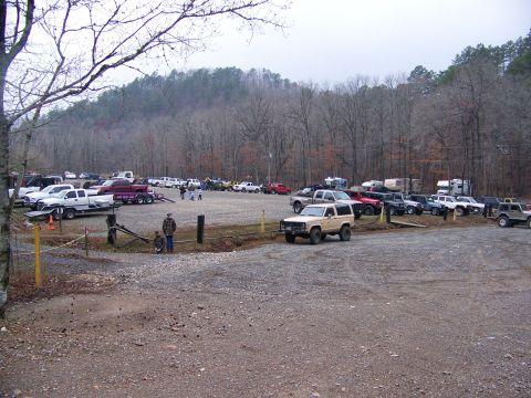 1992 Jeep YJ - A gravel parking lot is filled with numerous trucks and SUVs, with a tan Jeep YJ prominently displayed.