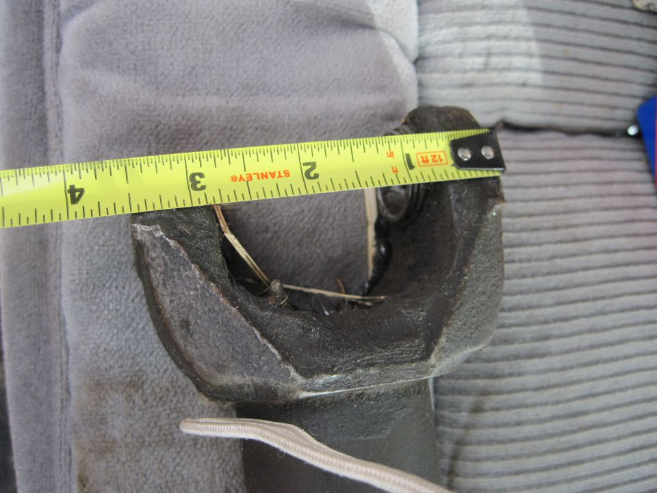 Close-up of a driveshaft yoke being measured with a yellow Stanley tape measure