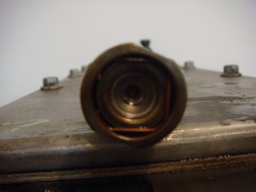 Close-up of a metal engine component with a circular opening showing internal coils