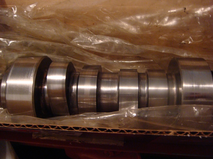 Polished steel engine crankshaft in a cardboard shipping box with plastic wrap folded back