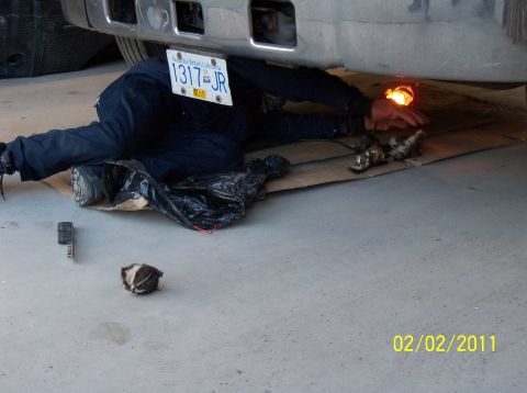 1989 Ford Bronco - A person is working on the underside of a vehicle, with a license plate visible.