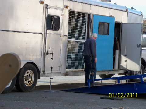 1989 Ford Bronco - A man stands by an open trailer, possibly for animal transport, with a ramp leading into it.