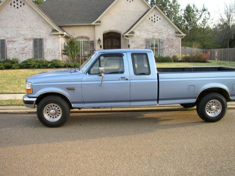 1995 Ford Bronco - This light blue pickup truck is parked on a suburban street in front of a house.