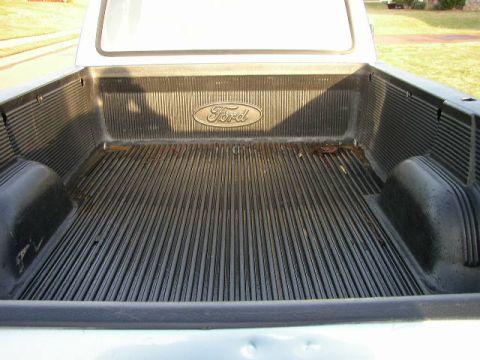 1995 Ford Bronco - The interior of a Ford pickup truck bed shows the iconic Ford oval emblem.
