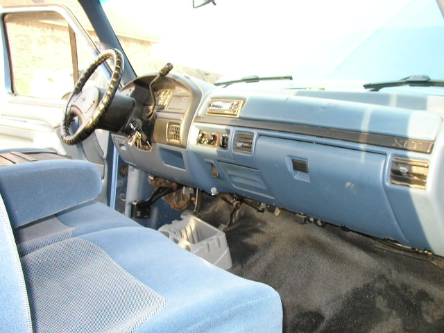 Blue fabric bench seat and dashboard of a truck, with a steering wheel and radio visible