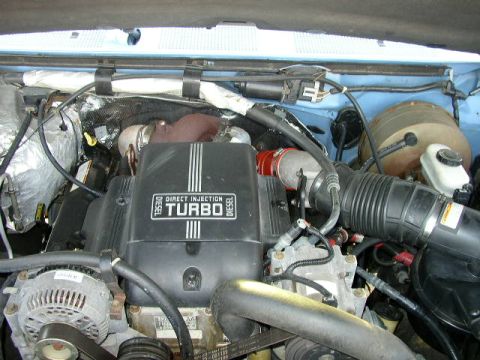 1995 Ford Bronco - Close-up of a diesel engine's turbocharger and intake system, with visible text on the cover.