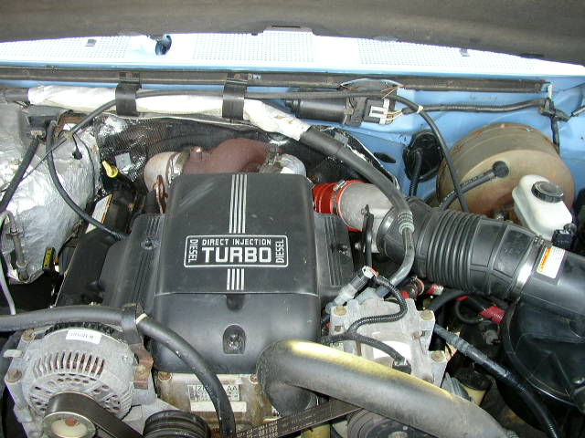 Engine bay showing turbocharger and intake system. Text on cover reads "DIRECT INJECTION TURBO DIESEL"