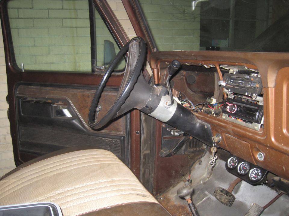 Interior shot of a vehicle's dashboard, showing the steering wheel, radio, and gauges. The interior appears worn