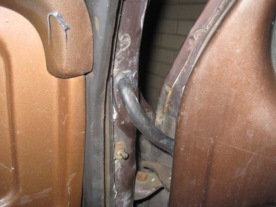 1979 Ford Bronco door jamb, brown exterior, showing rubber seal and metal frame with rust